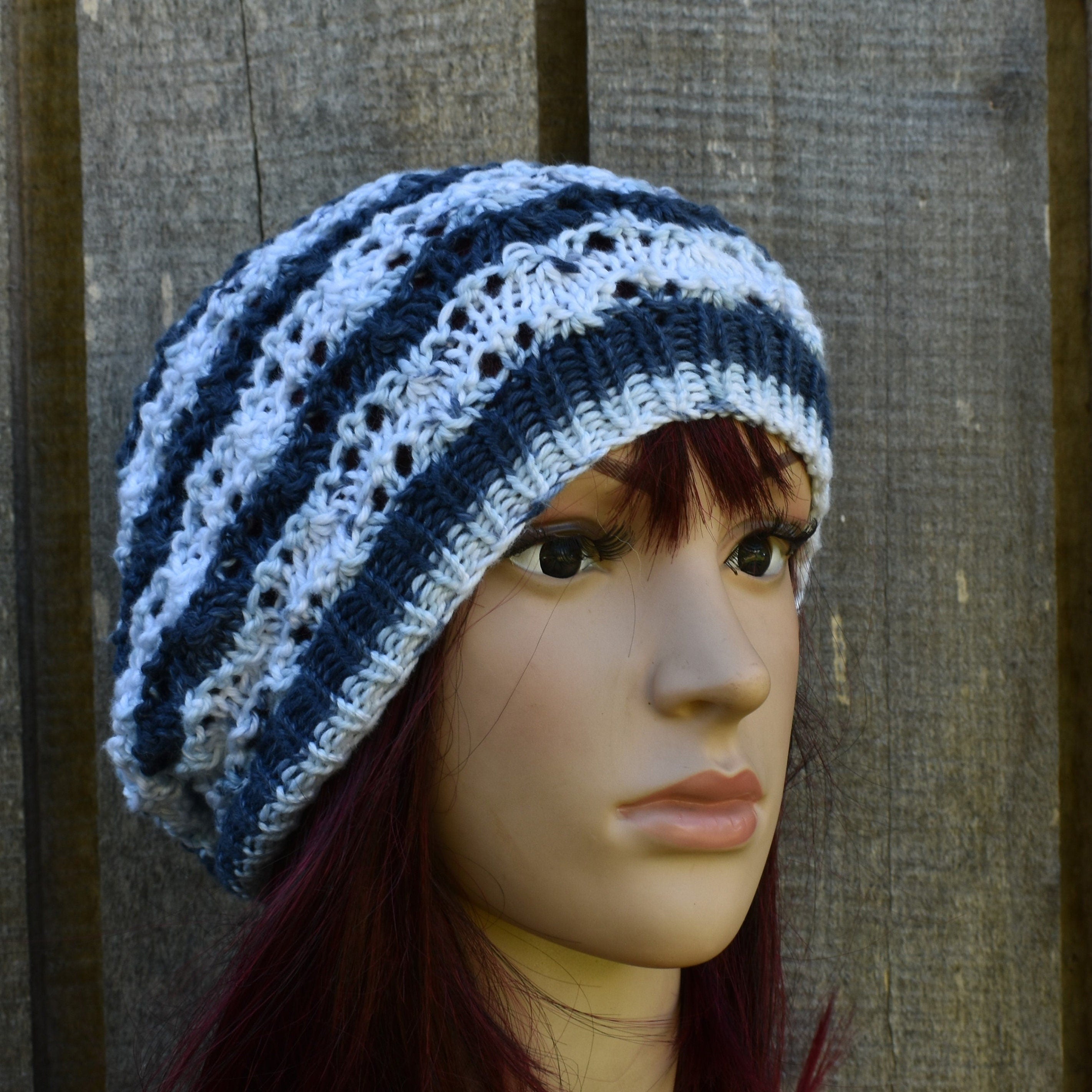 Knitted beanie with blue and white stripes on a mannequin head against a wooden background
