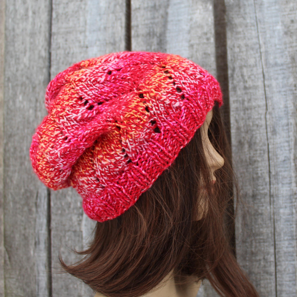 Knitted pink and orange beanie on a mannequin head against a wooden background