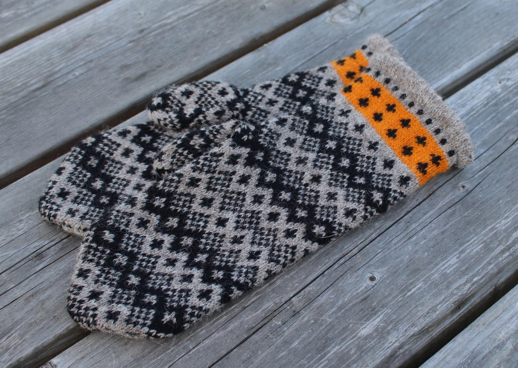 Knitted mittens with a geometric pattern on a wooden surface