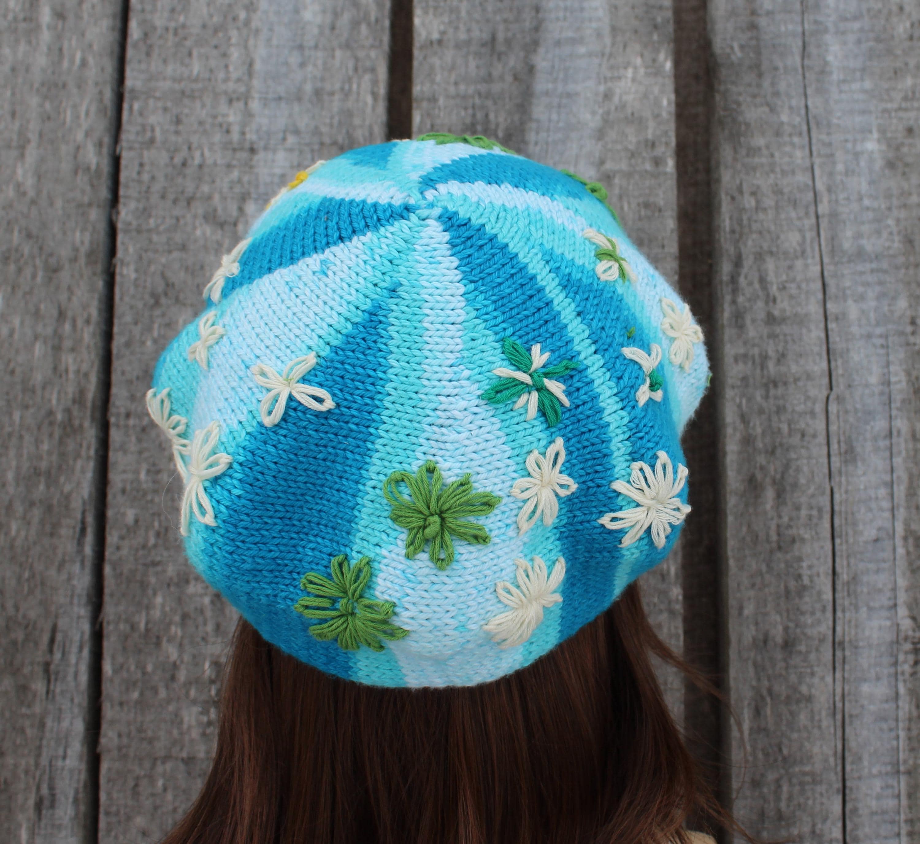 Blue knitted hat with floral patterns on a wooden background