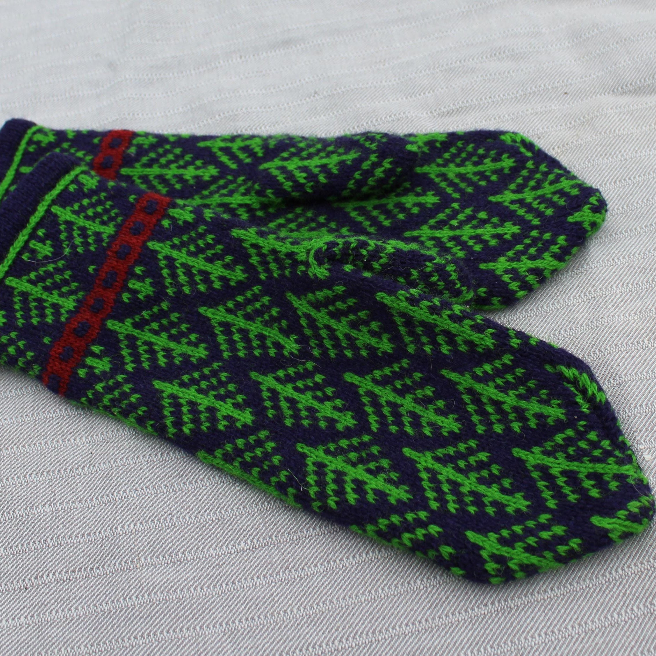 Pair of green and navy patterned mittens on a light gray background