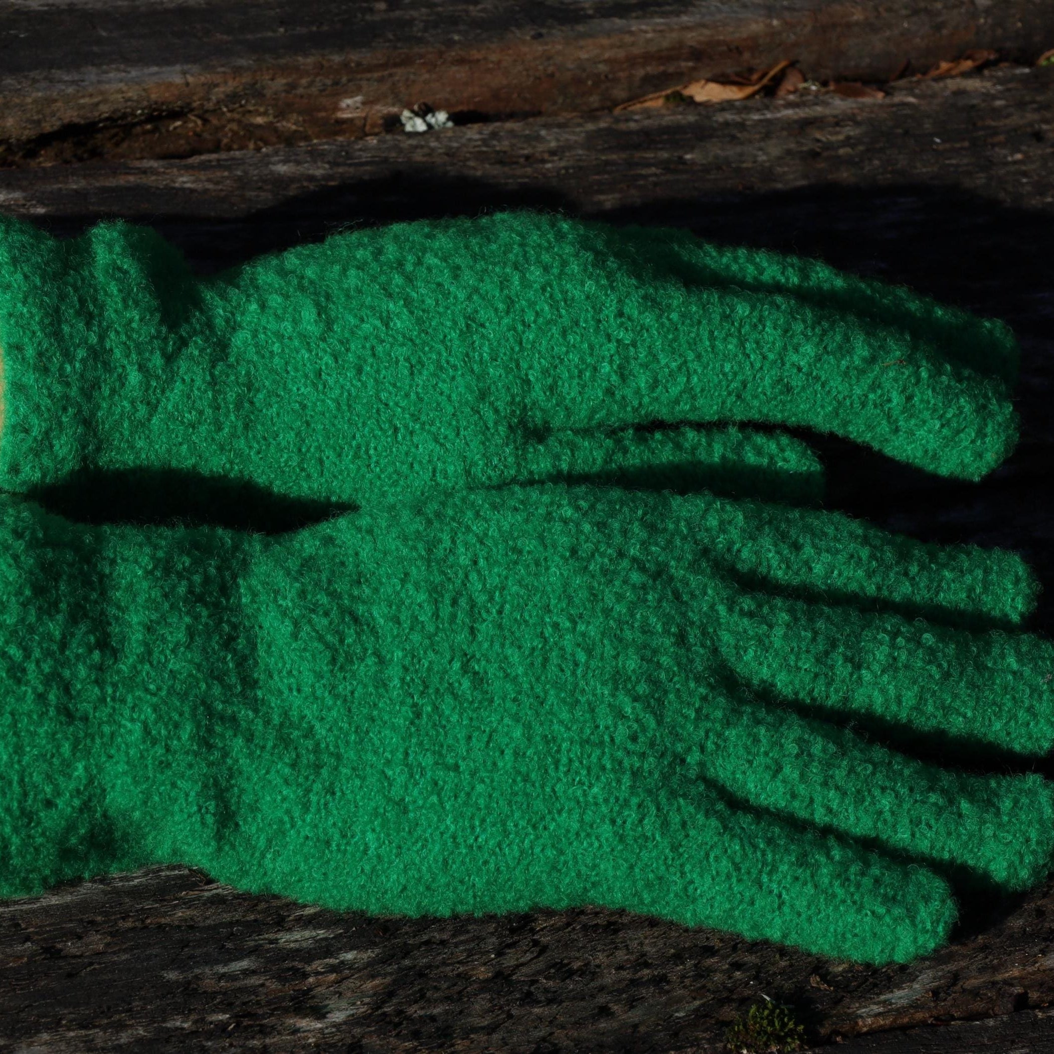 Green  gloves on a person's hands with a dark background
