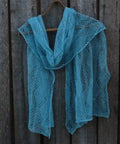 Blue knitted shawl on a wooden hanger against a wooden background