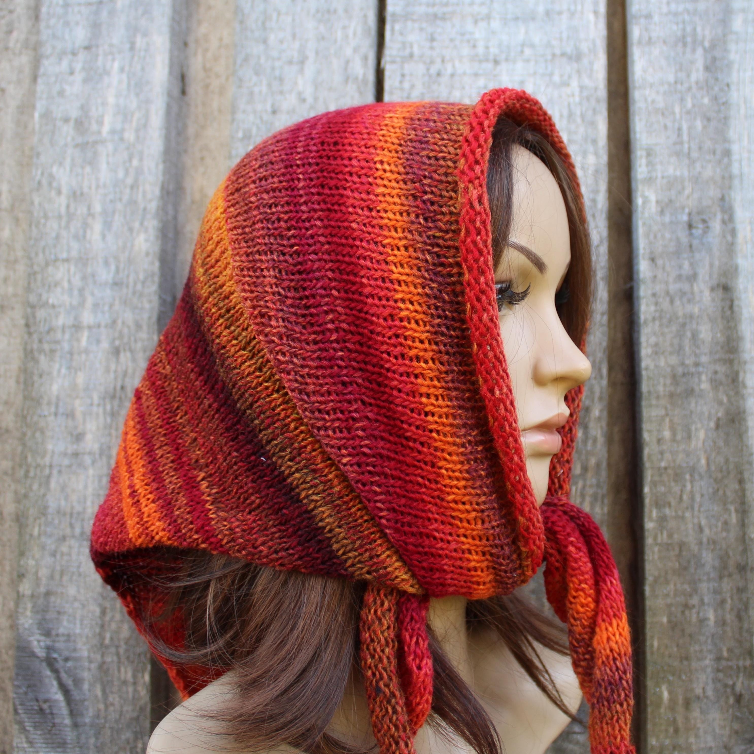 Mannequin wearing a red and orange striped knitted hood against a wooden background