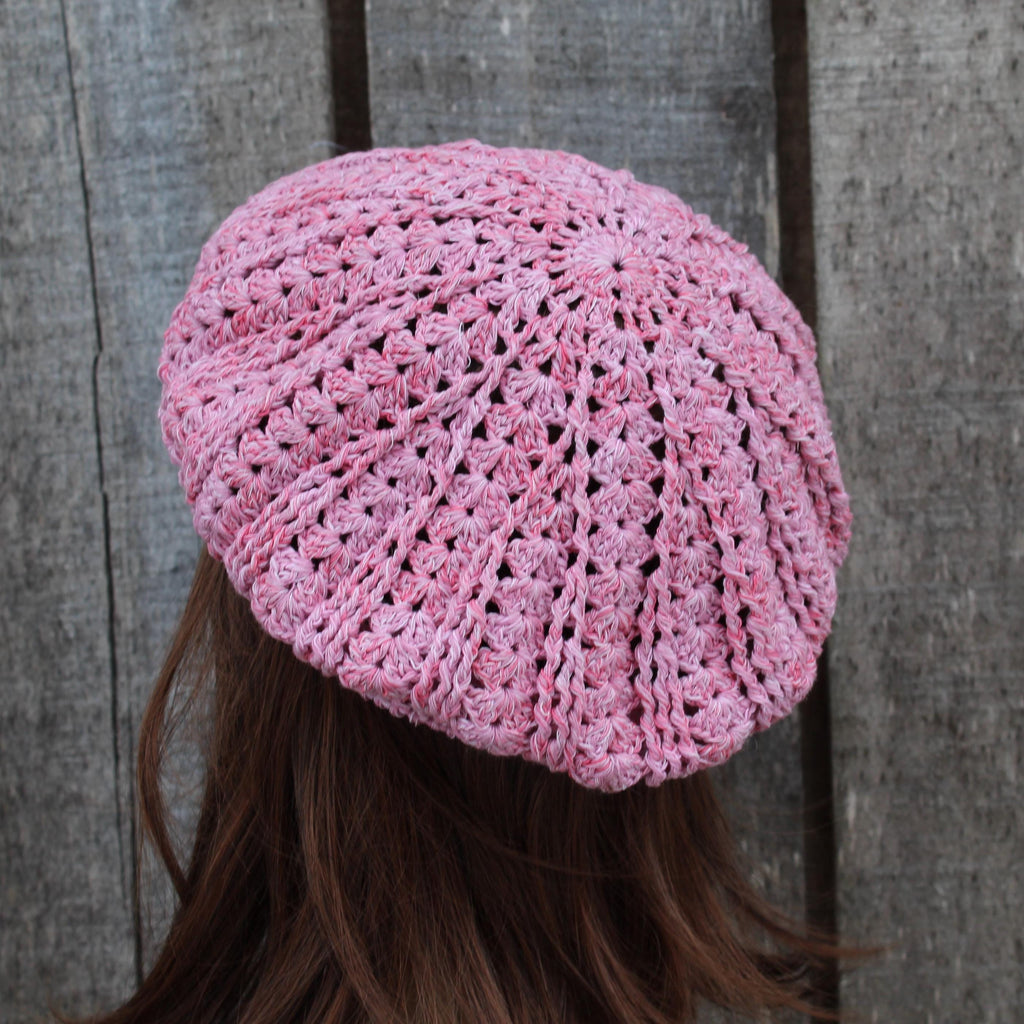 Pink crocheted beanie worn by a person against a wooden background