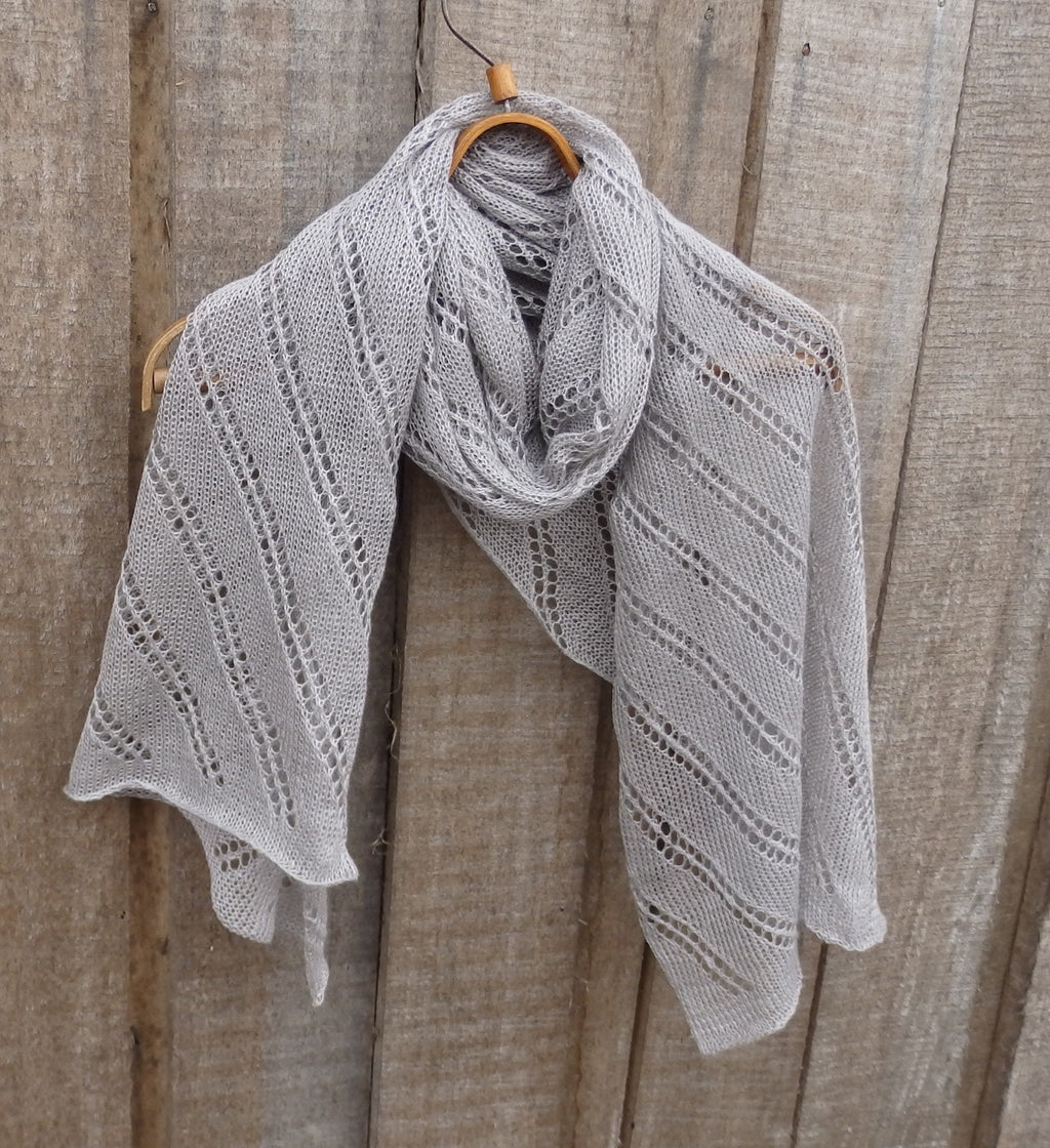 Knitted gray shawl draped over a wooden surface