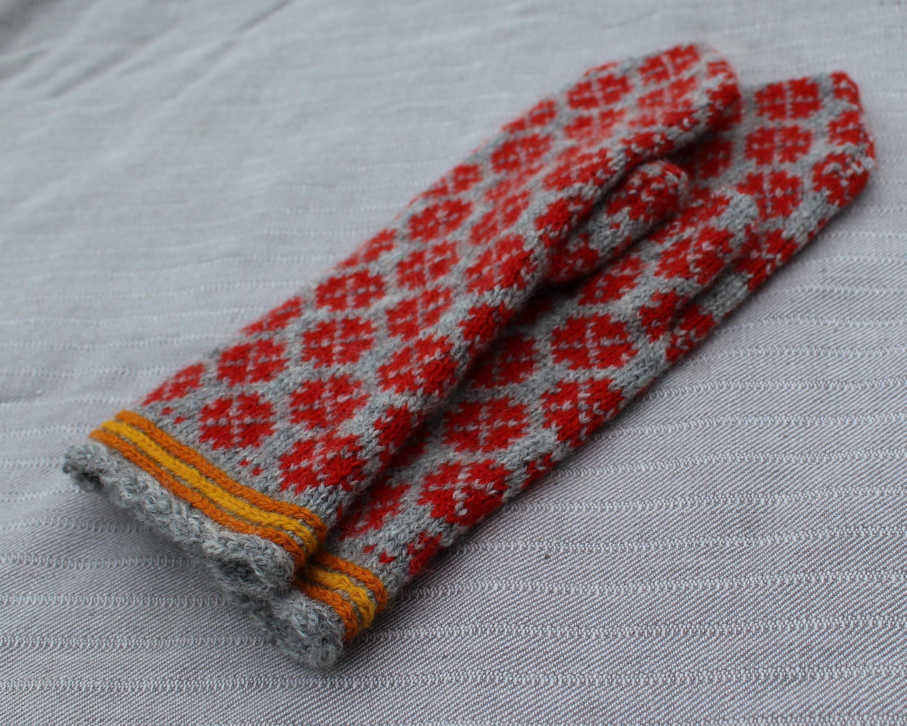 Pair of gray and red patterned mittens on a light gray background