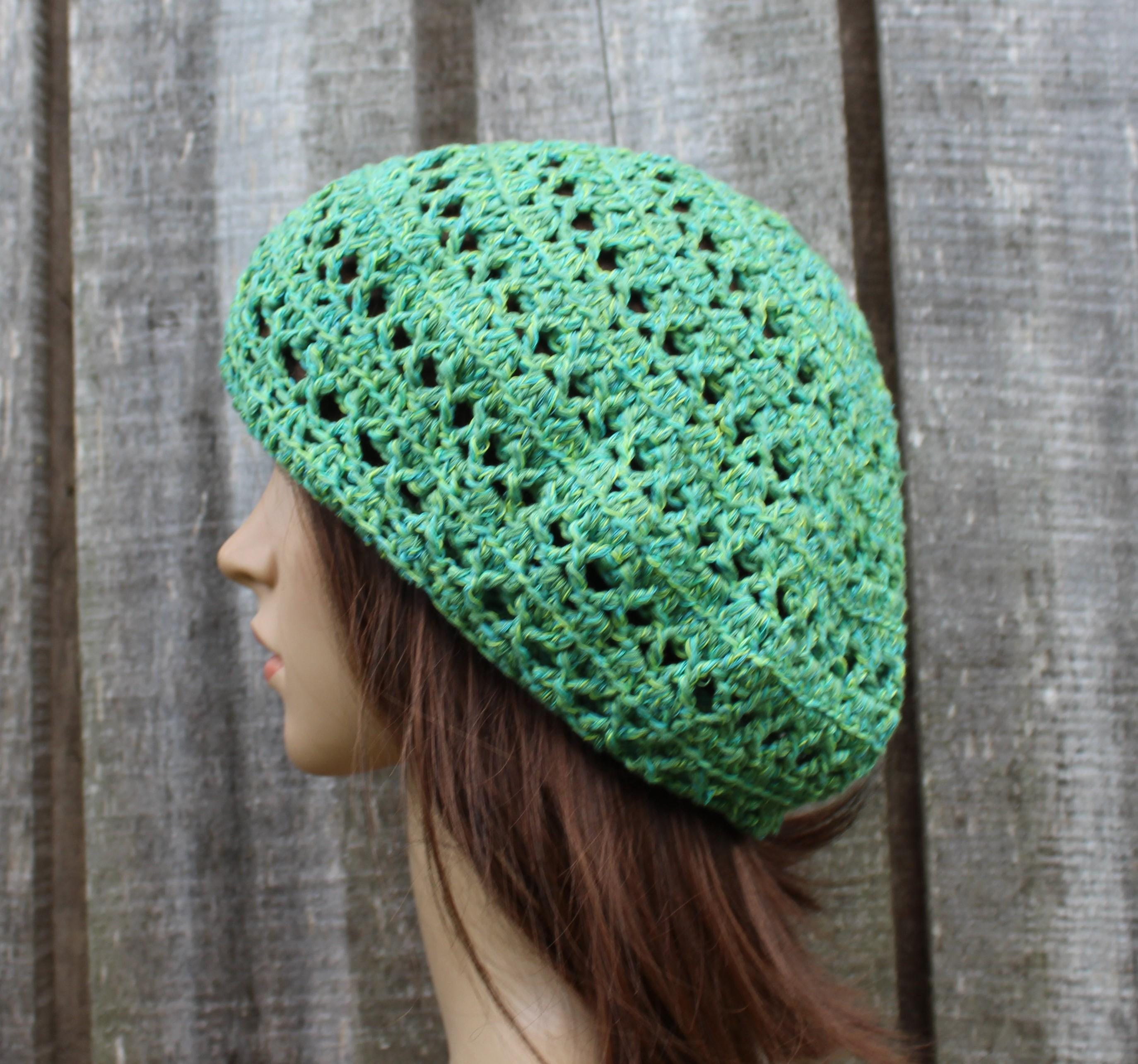 Green crocheted beanie on a mannequin head against a wooden background