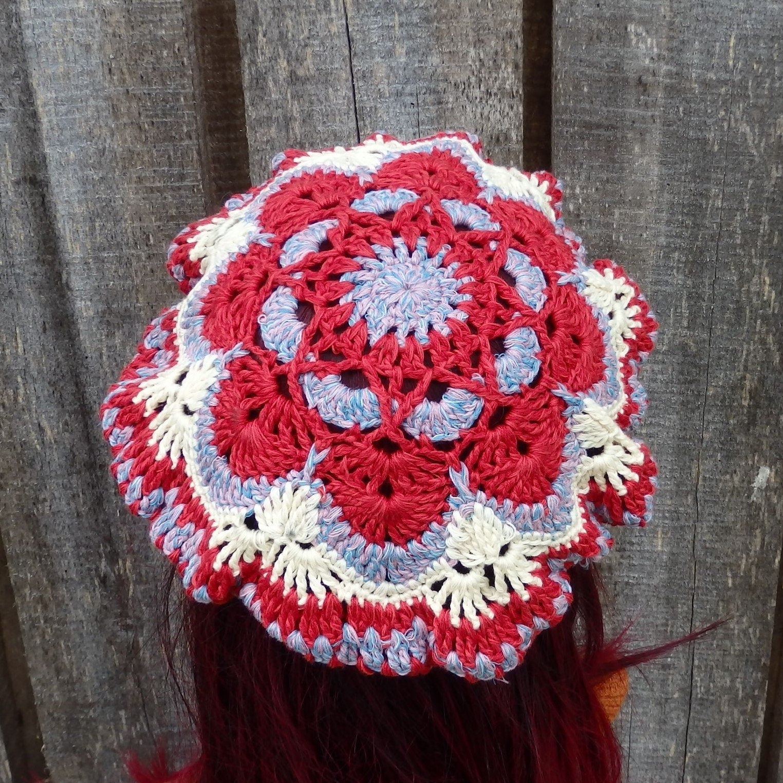 Crocheted headband with red, white, and blue pattern against a wooden background