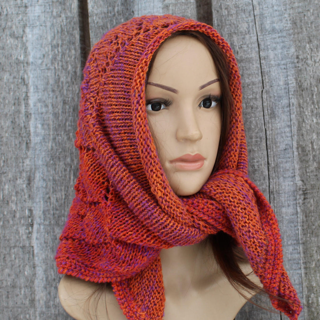 Mannequin head wearing a orange knitted scarf against a wooden background