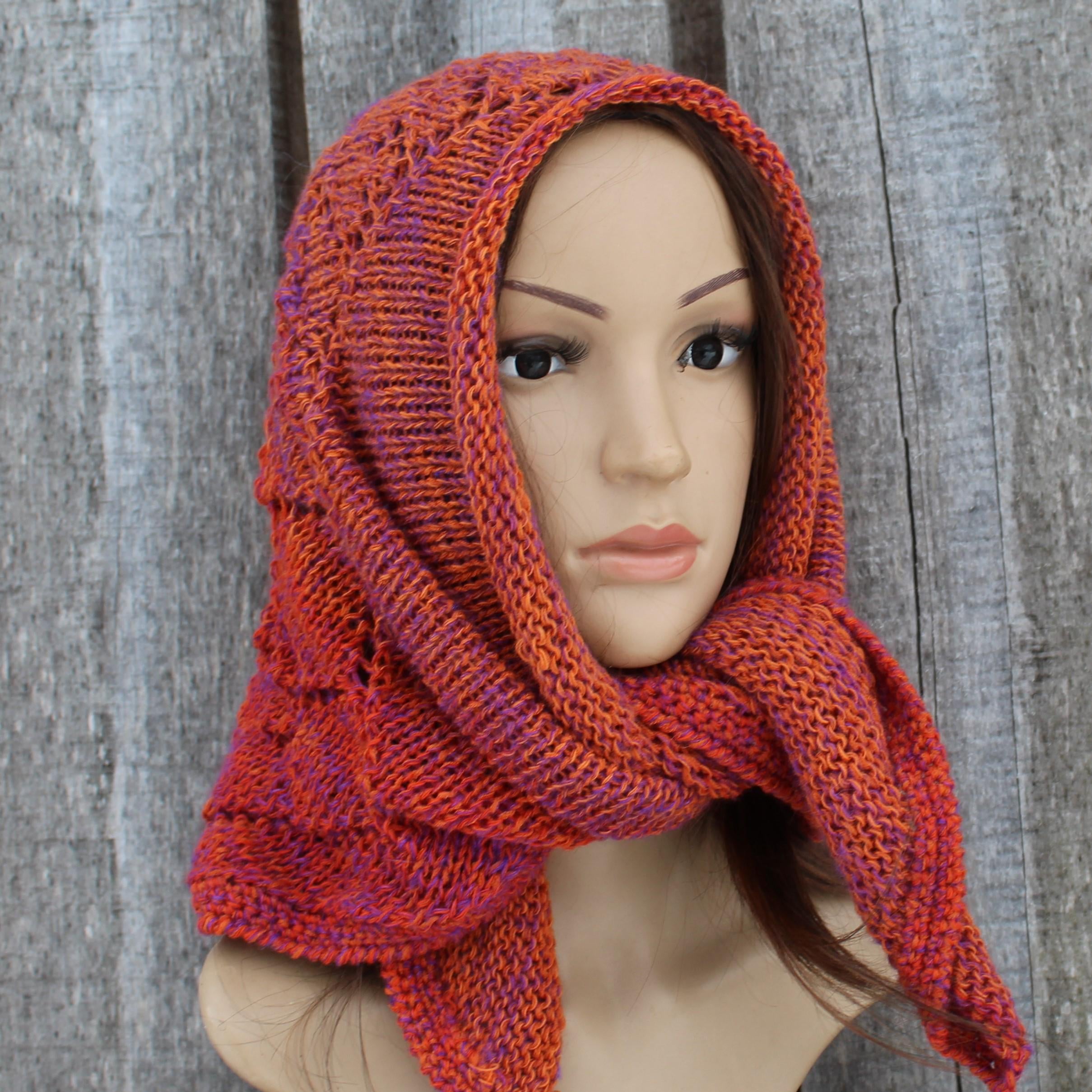 Mannequin head wearing a orange knitted scarf against a wooden background