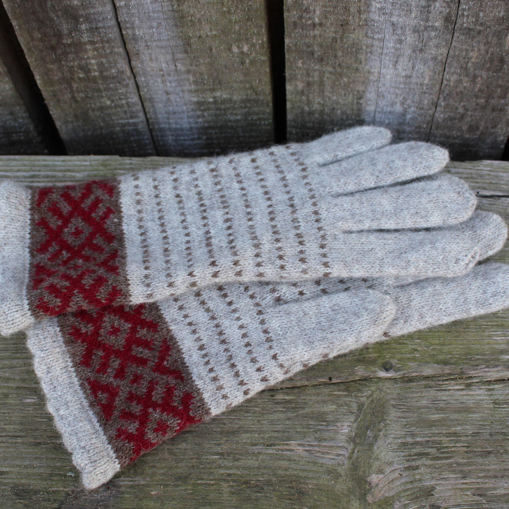 Pair of gray gloves with red pattern on a wooden surface