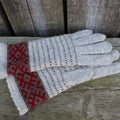 Pair of gray gloves with red pattern on a wooden surface