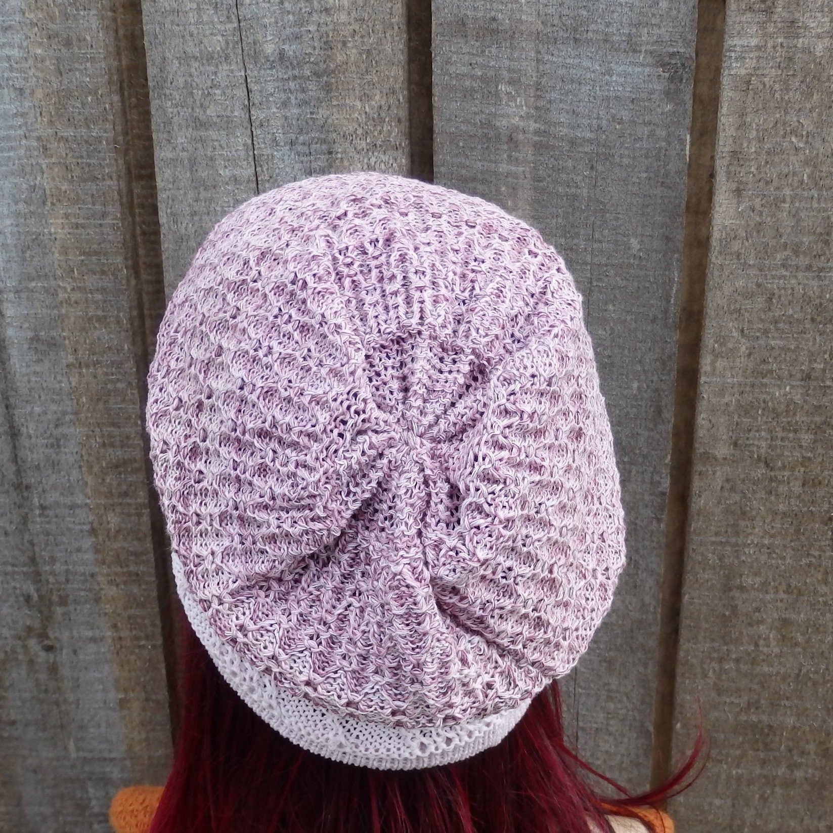 Purple textured beanie on a person with red hair against a wooden background