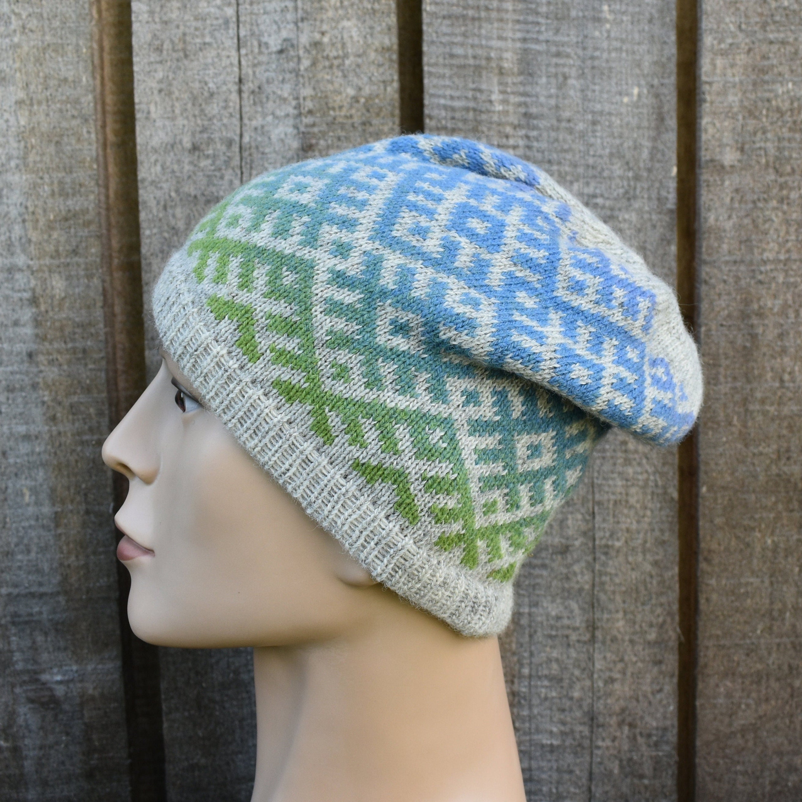 Knitted hat with a geometric pattern on a mannequin head against a wooden background