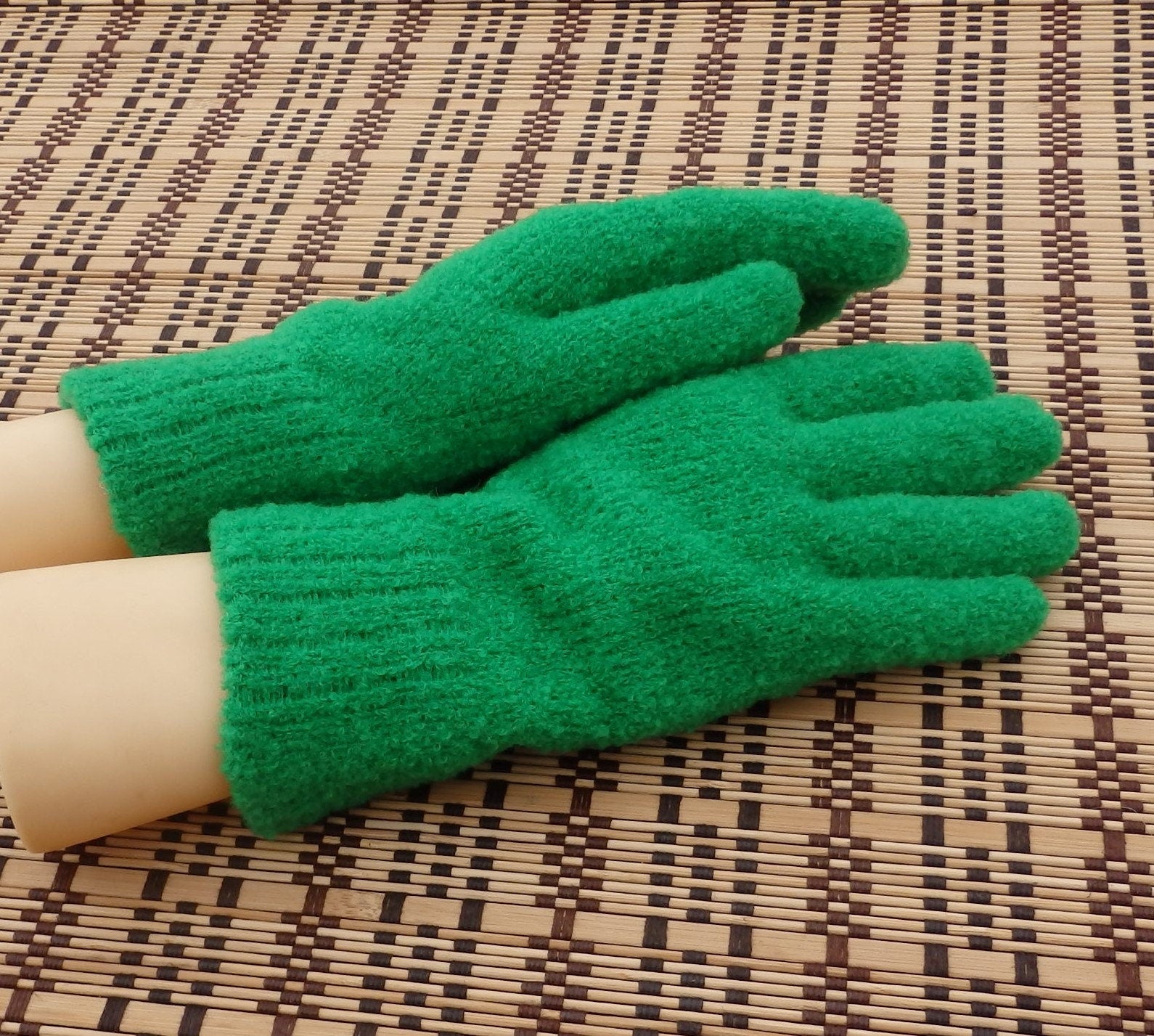 Green gloves on a person's hands on a woven mat background