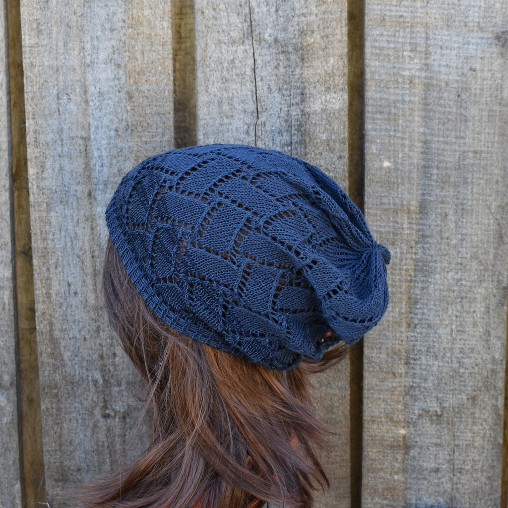 Blue knitted beanie worn by a person with brown hair against a wooden background