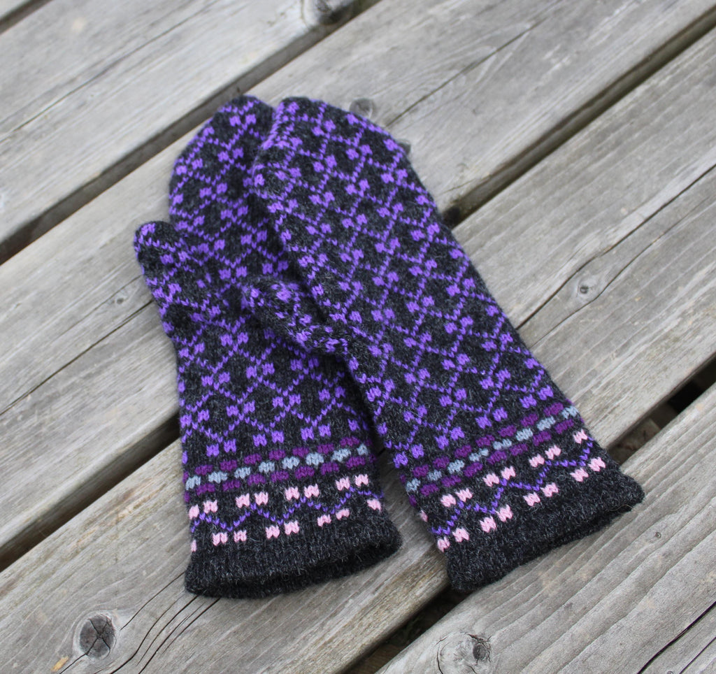 Pair of black and purple patterned gloves on a wooden surface