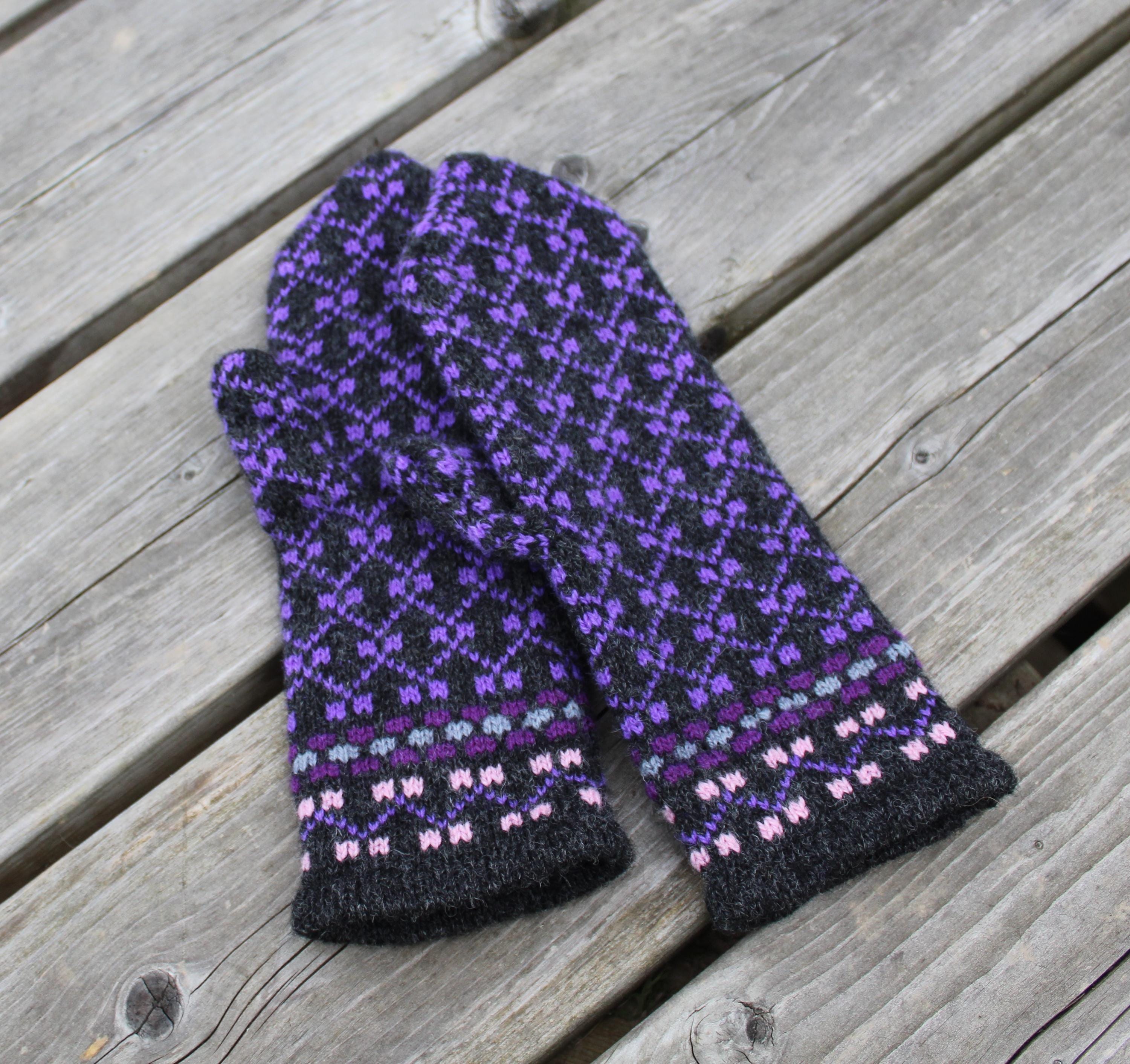 Pair of black and purple patterned gloves on a wooden surface