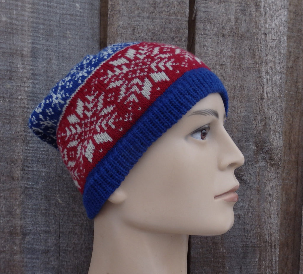 Knitted hat with red, blue, and white pattern on a mannequin head against a wooden background