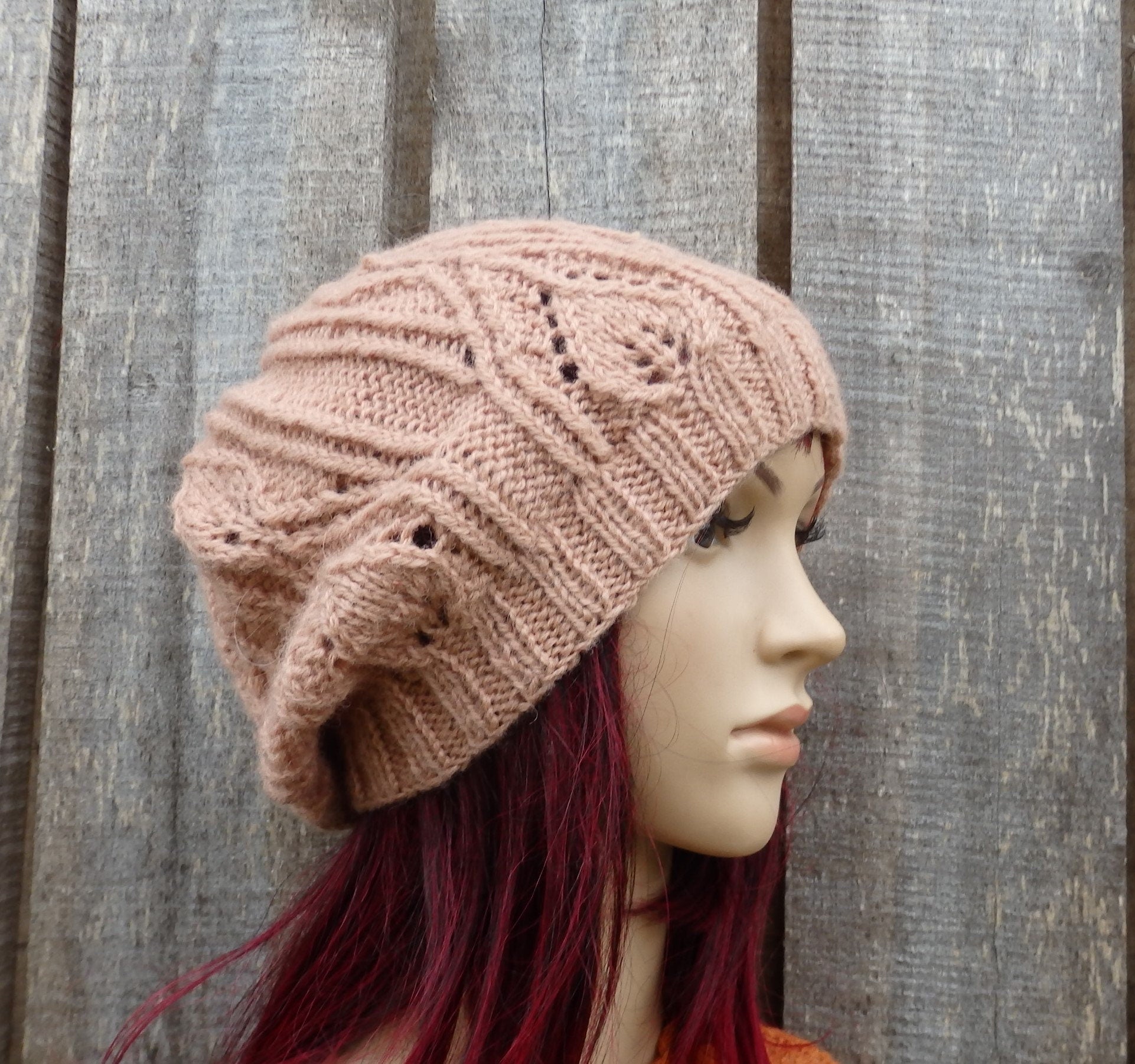 Knitted pink beanie on a mannequin head against a wooden background