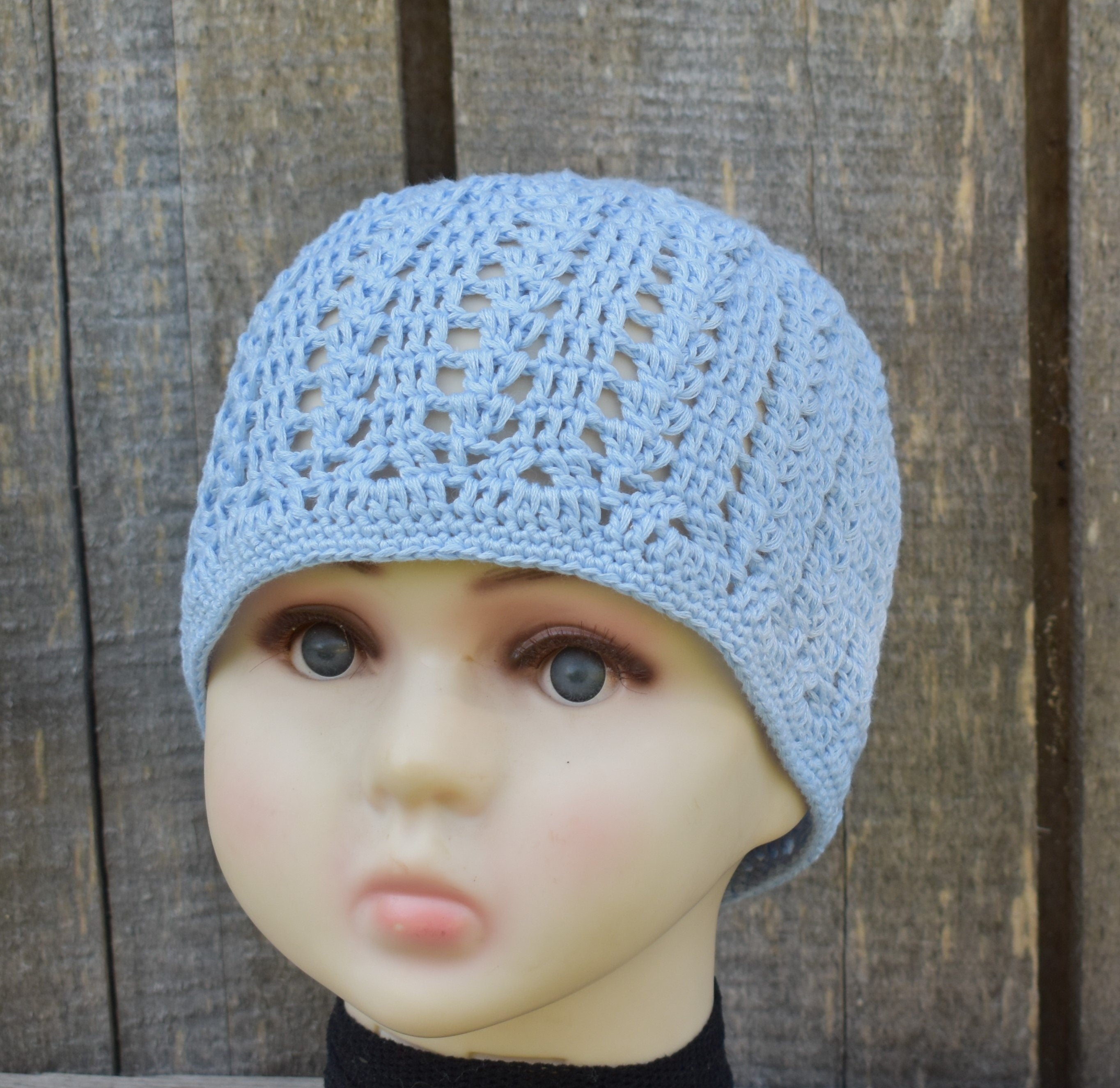 Blue crochet hat on a mannequin head against a wooden background