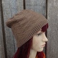 Mannequin head wearing a brown knitted beanie against a wooden panel background
