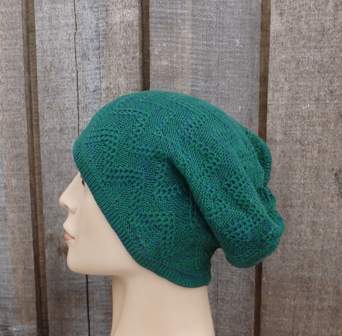 Green knitted beanie on a mannequin head against a wooden background