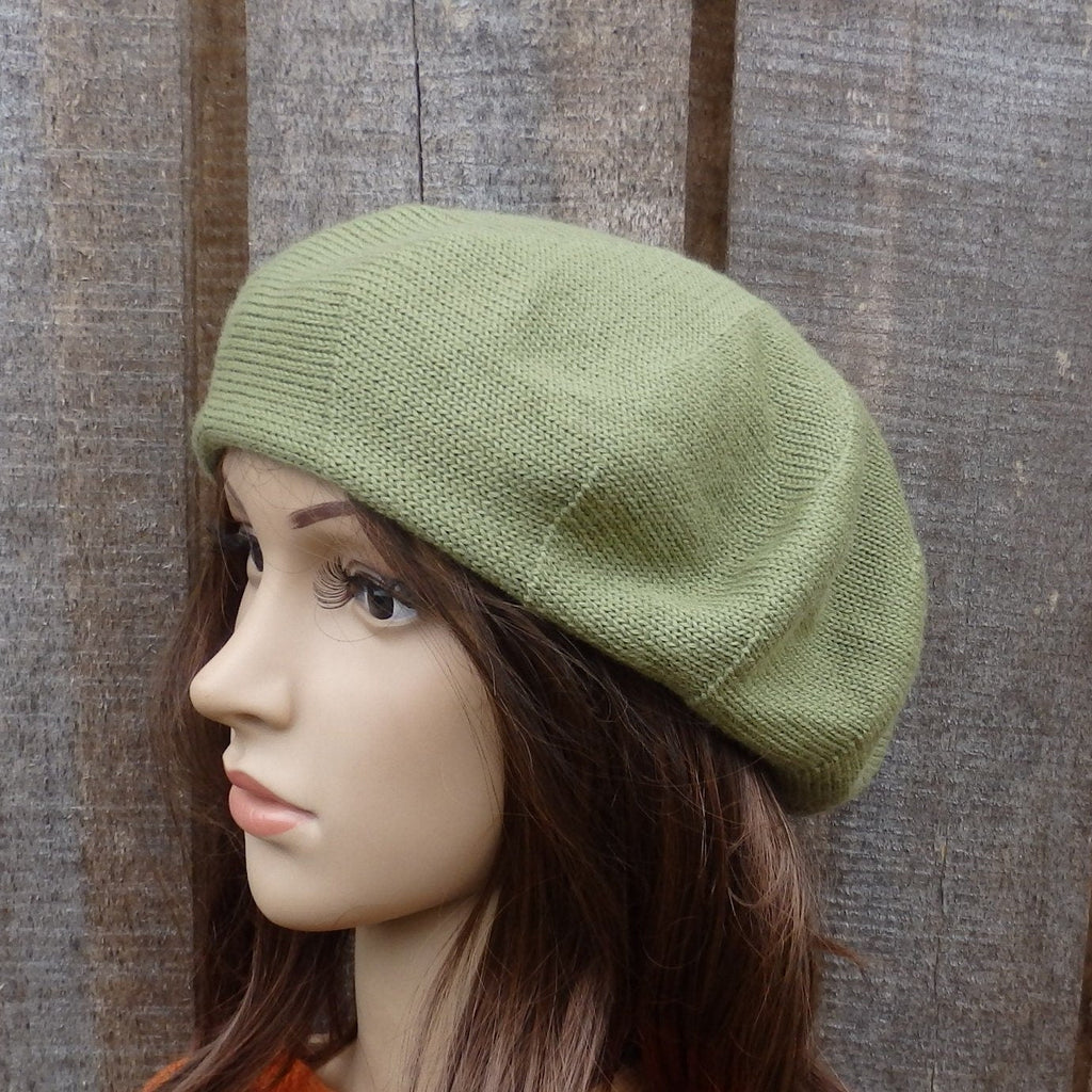 Green knitted beret on a mannequin head against a wooden background