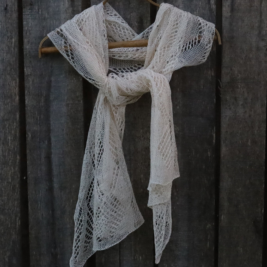 Linen lace scarf draped over a wooden hanger against a dark wooden background