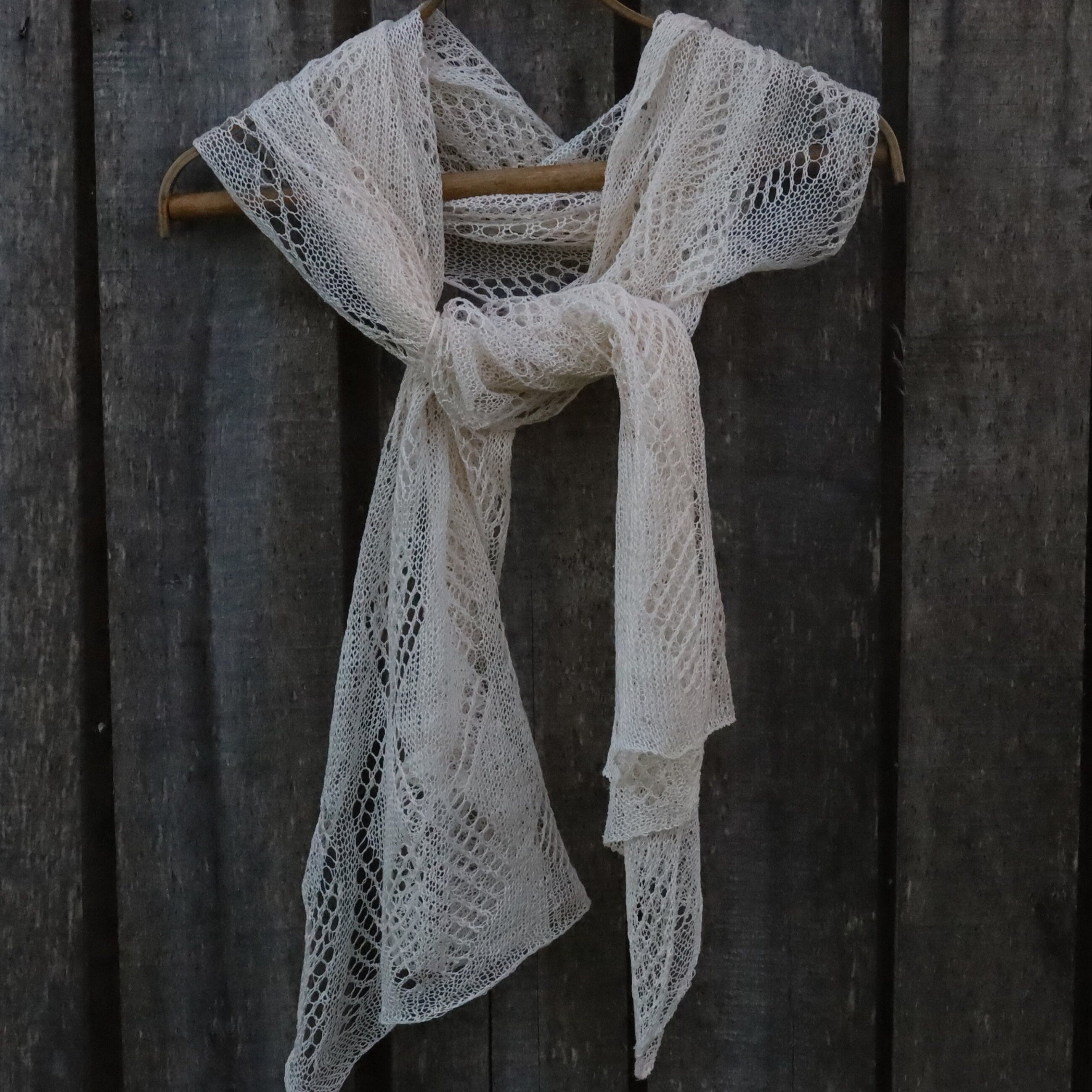 Linen lace scarf draped over a wooden hanger against a dark wooden background