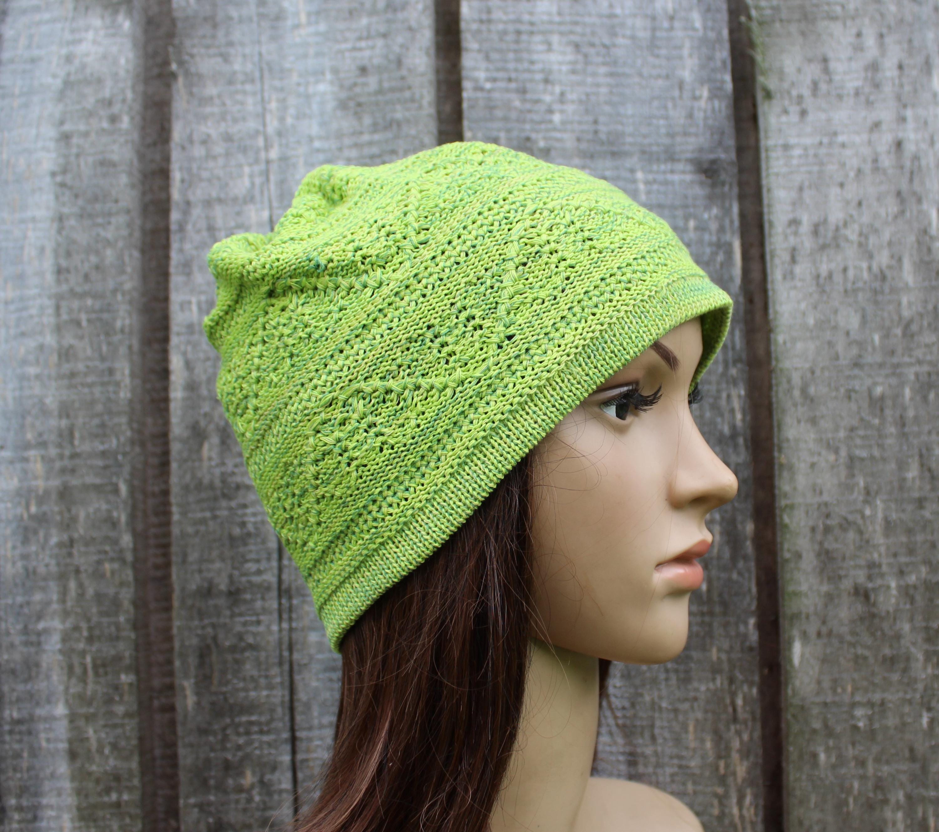 Green knitted hat on a mannequin head against a wooden background