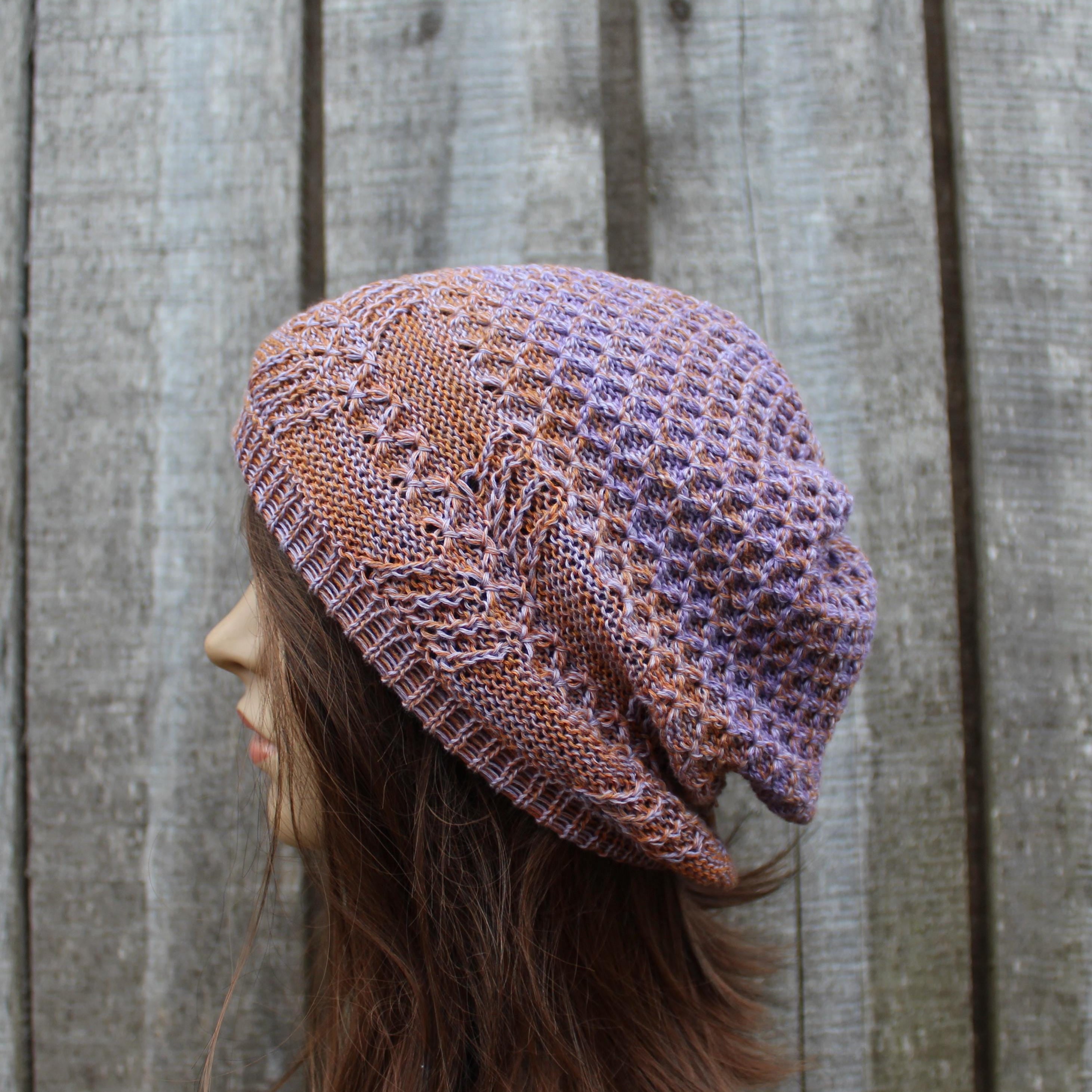 Person wearing a patterned knit hat against a wooden fence background