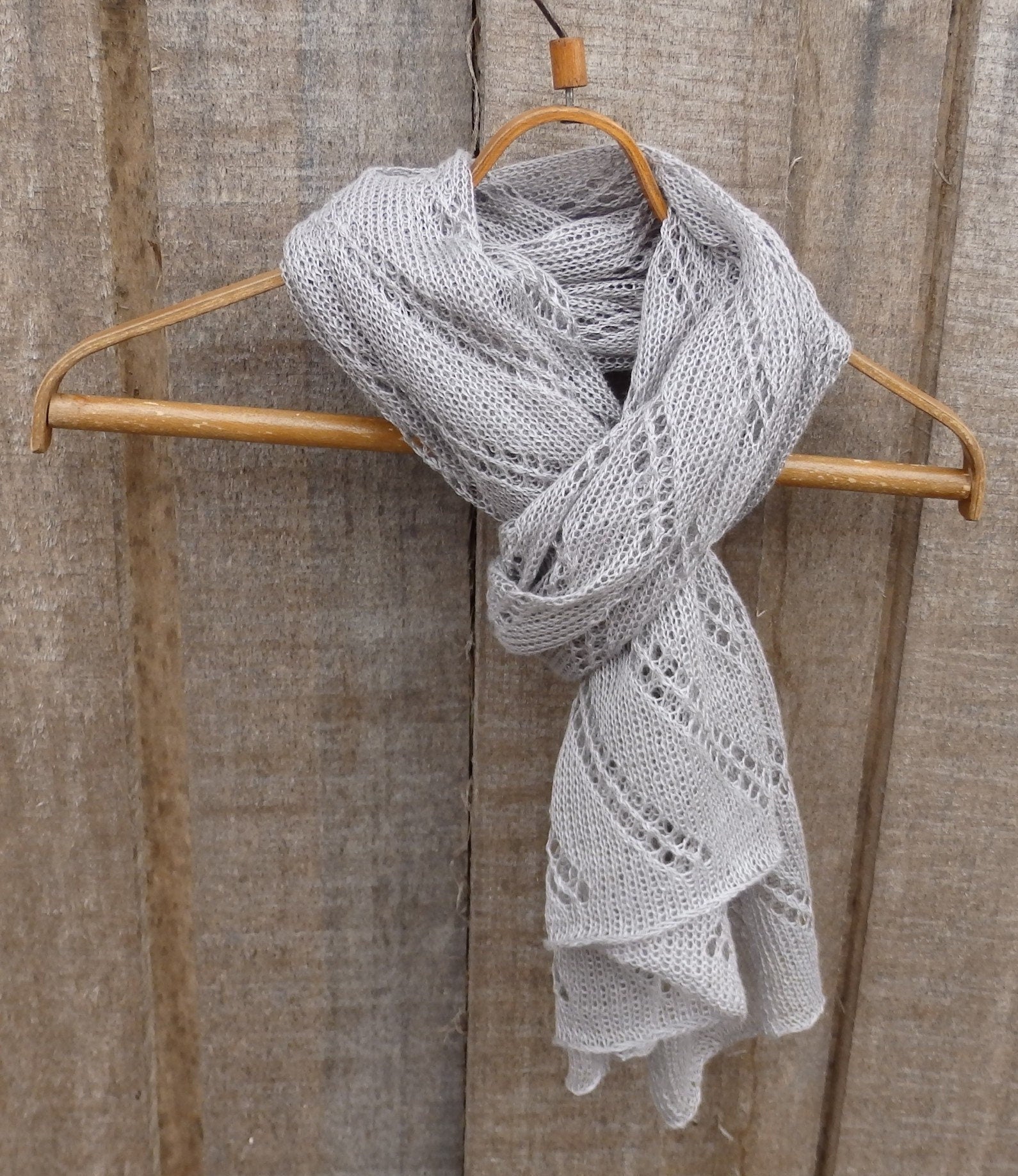 Gray knitted scarf on a wooden hanger against a wooden background
