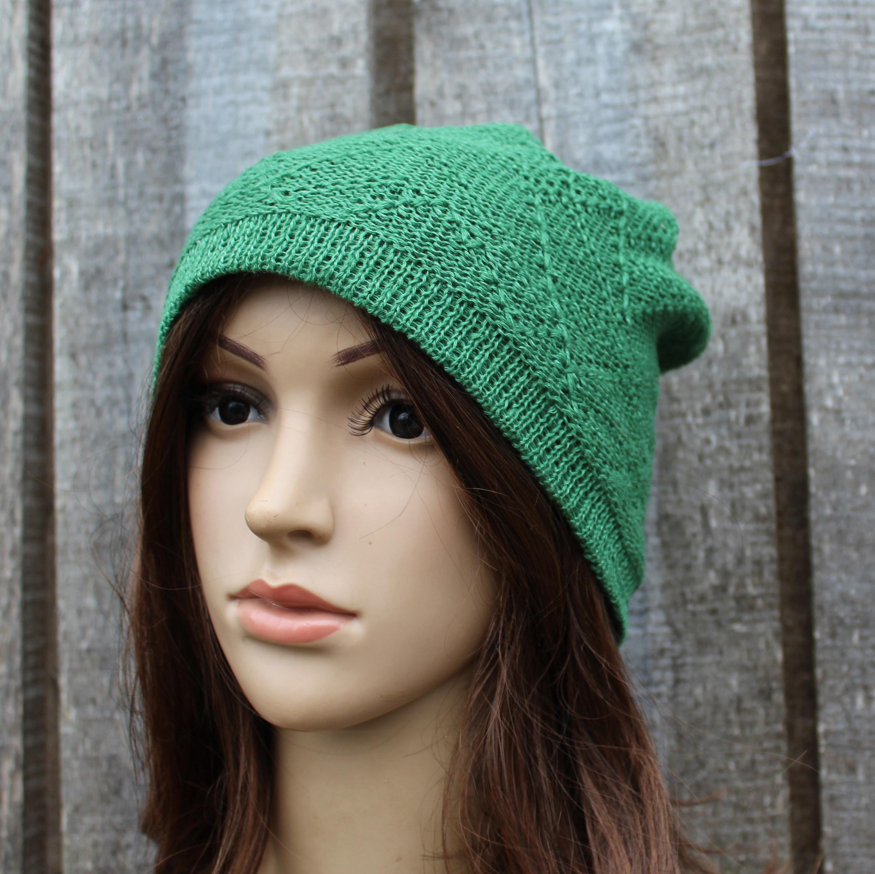 Green knitted beanie on a mannequin head against a wooden background