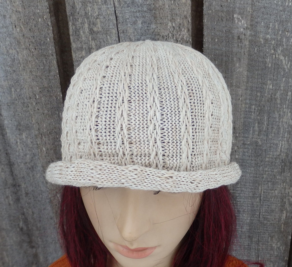 Knitted beige cap on a mannequin head against a wooden background