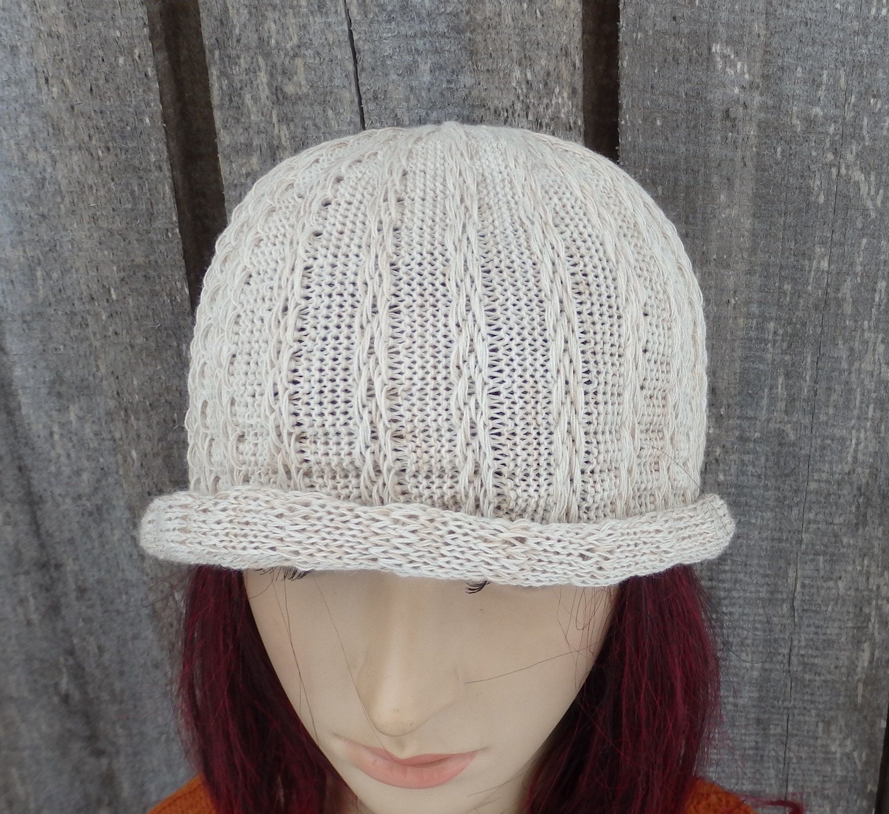 Knitted beige cap on a mannequin head against a wooden background