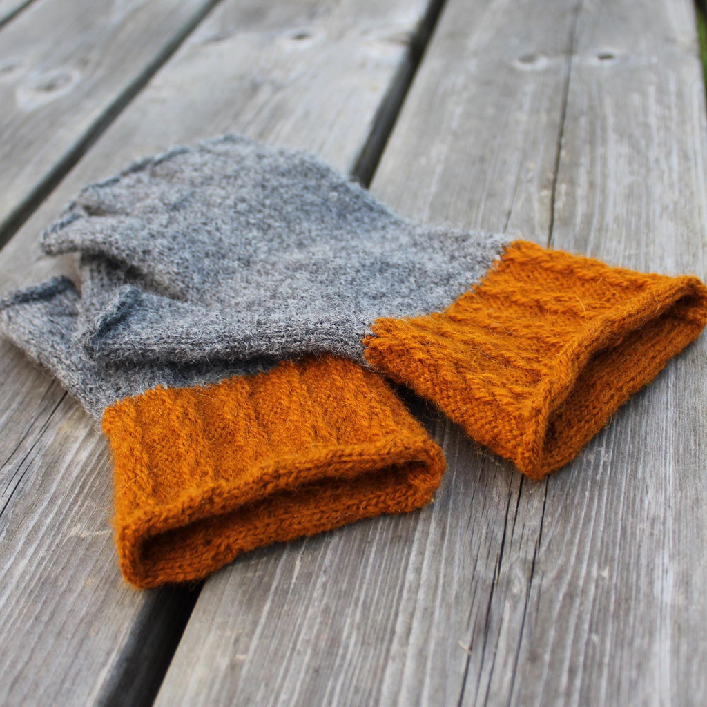 Pair of gray and orange knitted gloves on a wooden surface