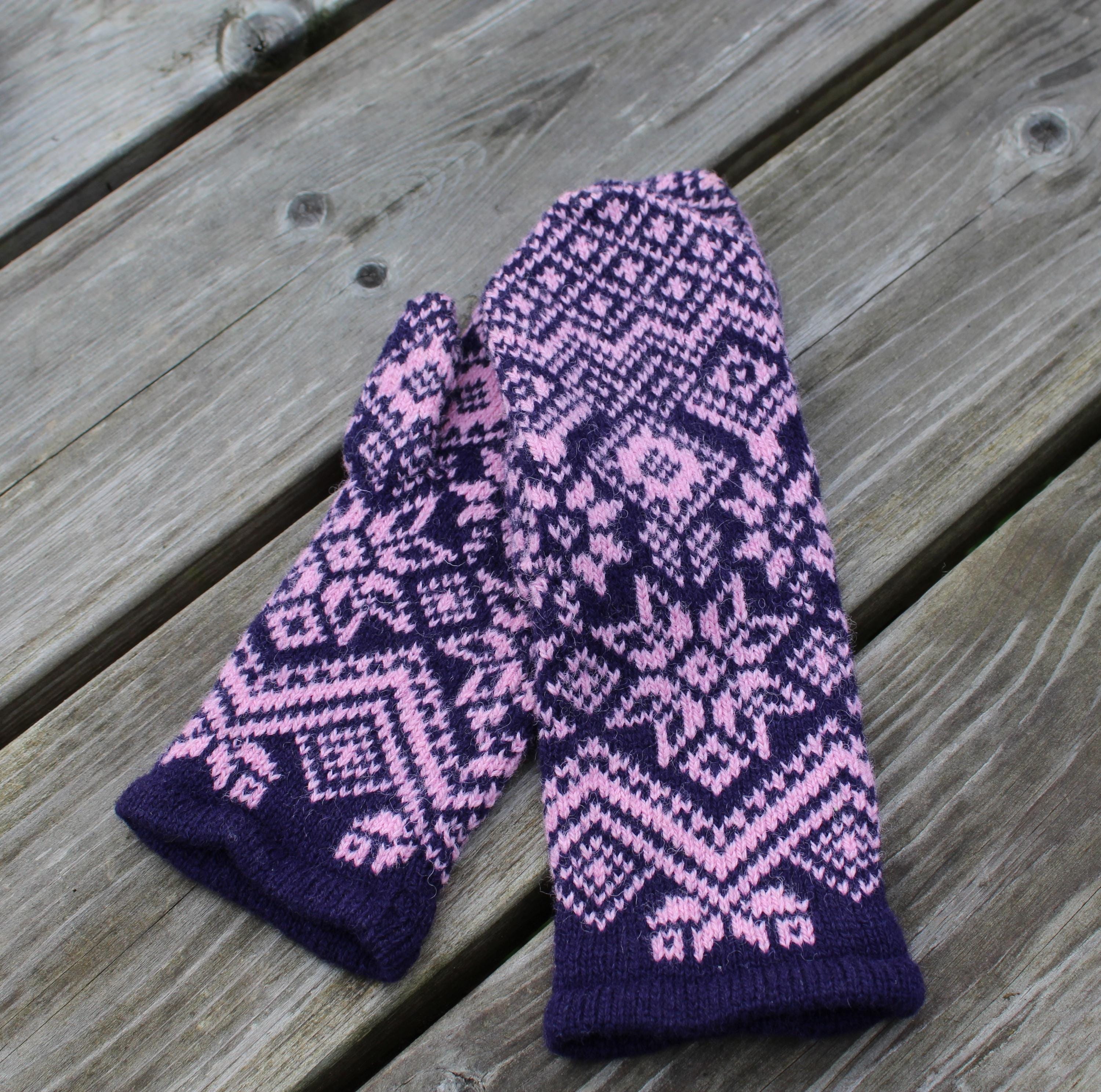 Pair of purple and pink patterned mittens on a wooden surface