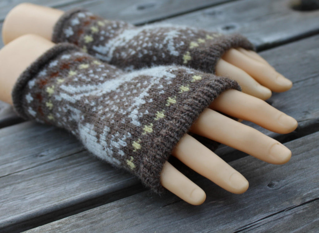 Pair of brown and white patterned fingerless gloves on a wooden surface