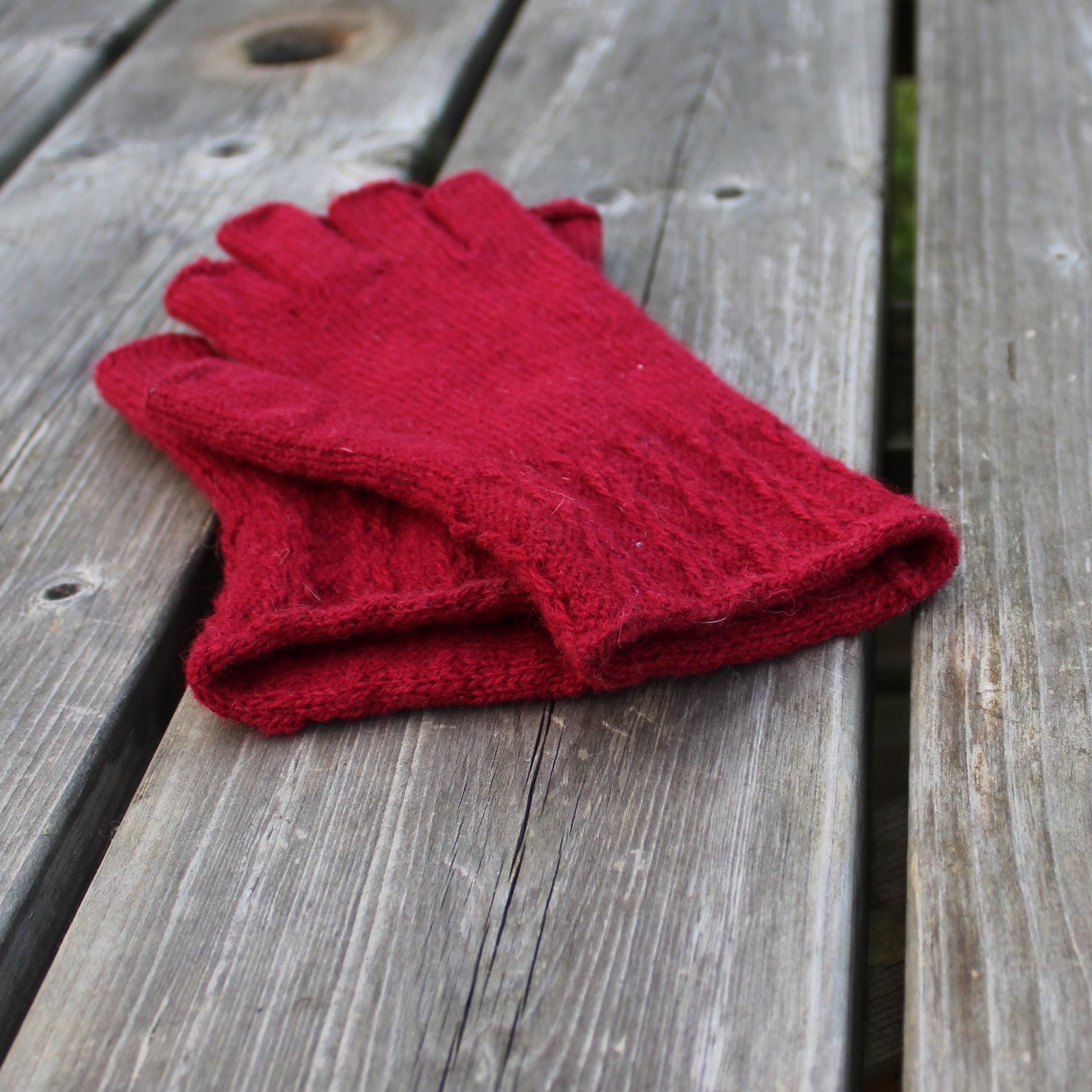Red knitted glove on a wooden surface