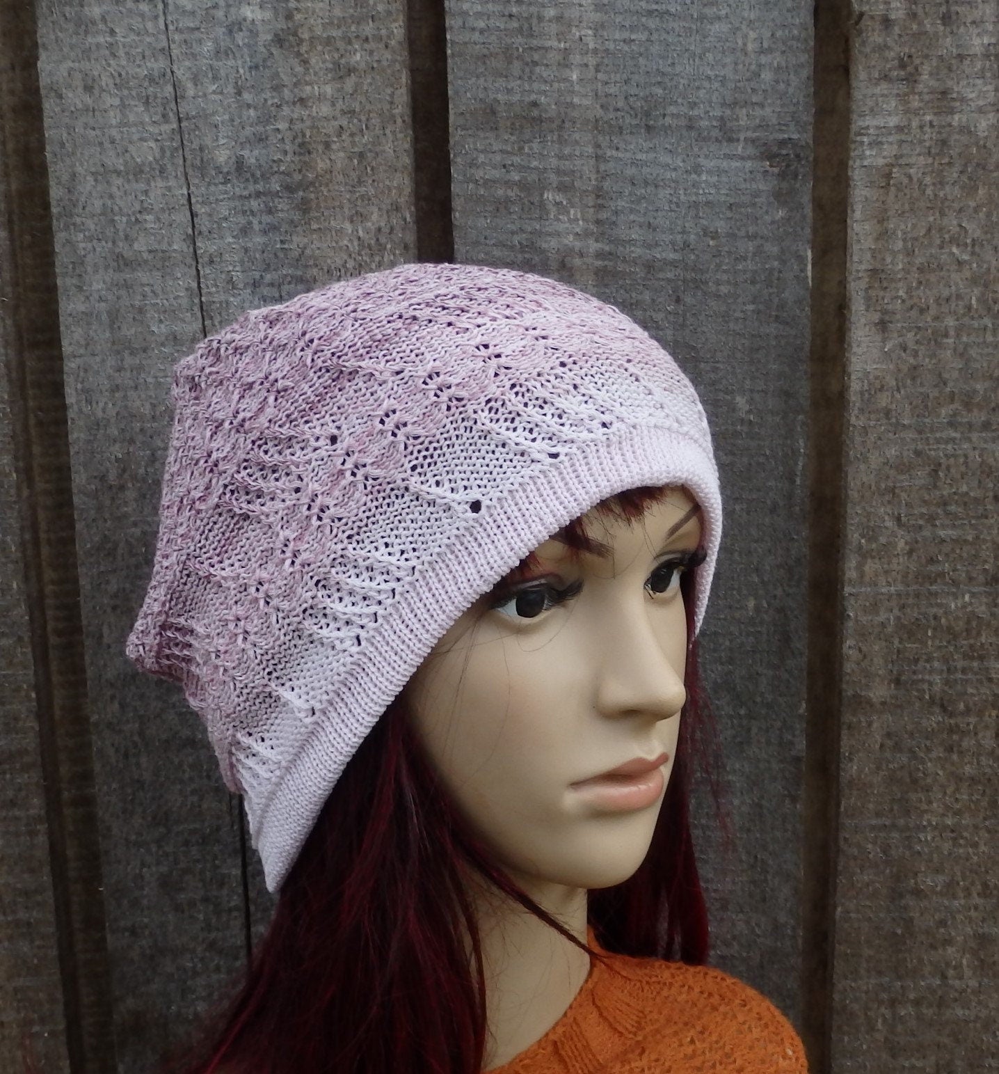 Mannequin head wearing a light purple knitted hat against a wooden background