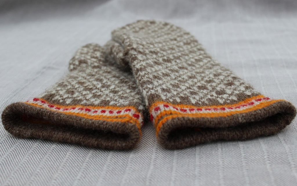 Pair of knitted mittens with a patterned cuff on a light fabric background