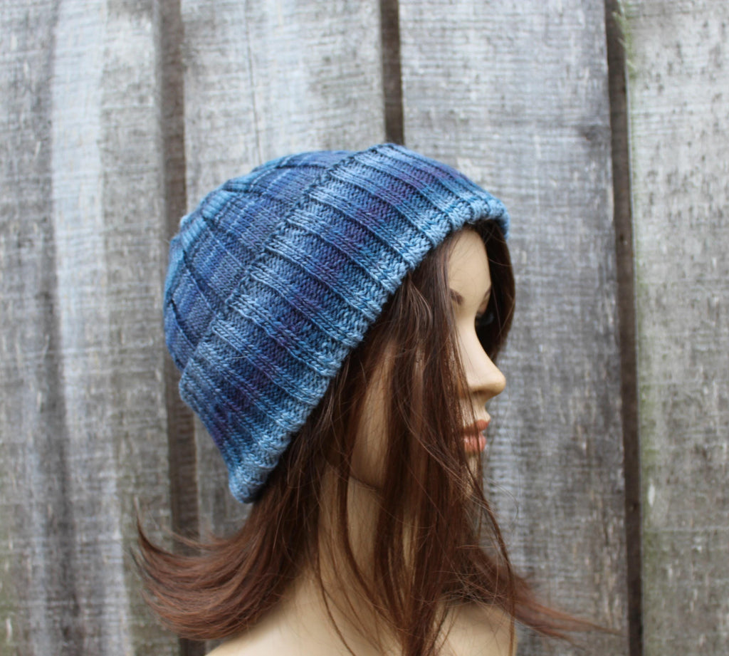Blue knitted beanie on a mannequin head against a wooden background