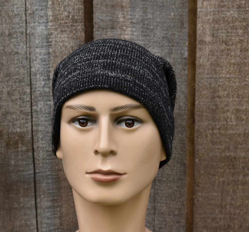 Mannequin head wearing a black knit beanie against a wooden background