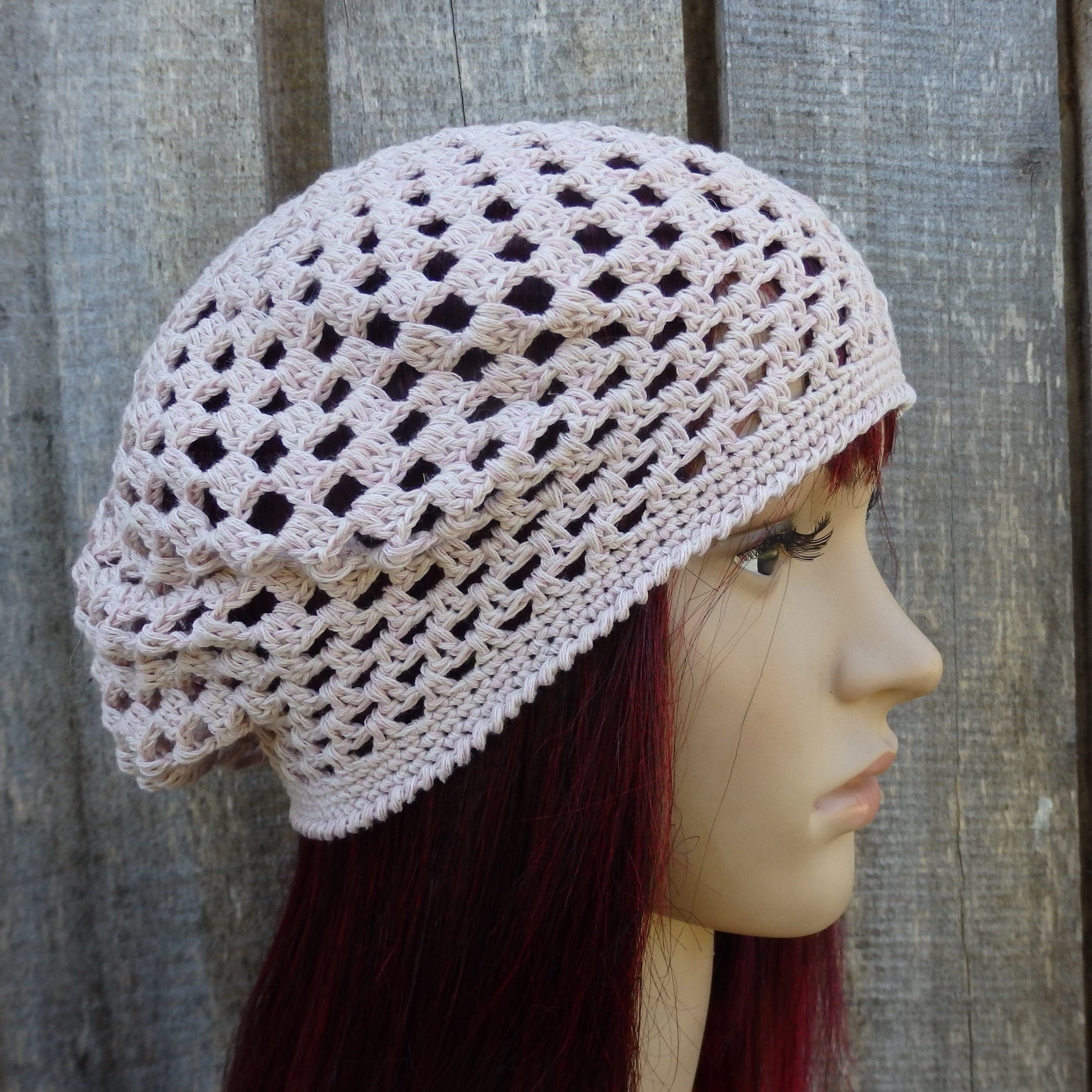 Crocheted beige cap on a mannequin head against a wooden background