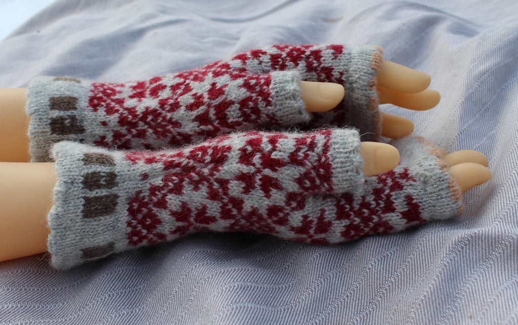 Pair of knitted fingerless gloves with a pattern on a fabric background