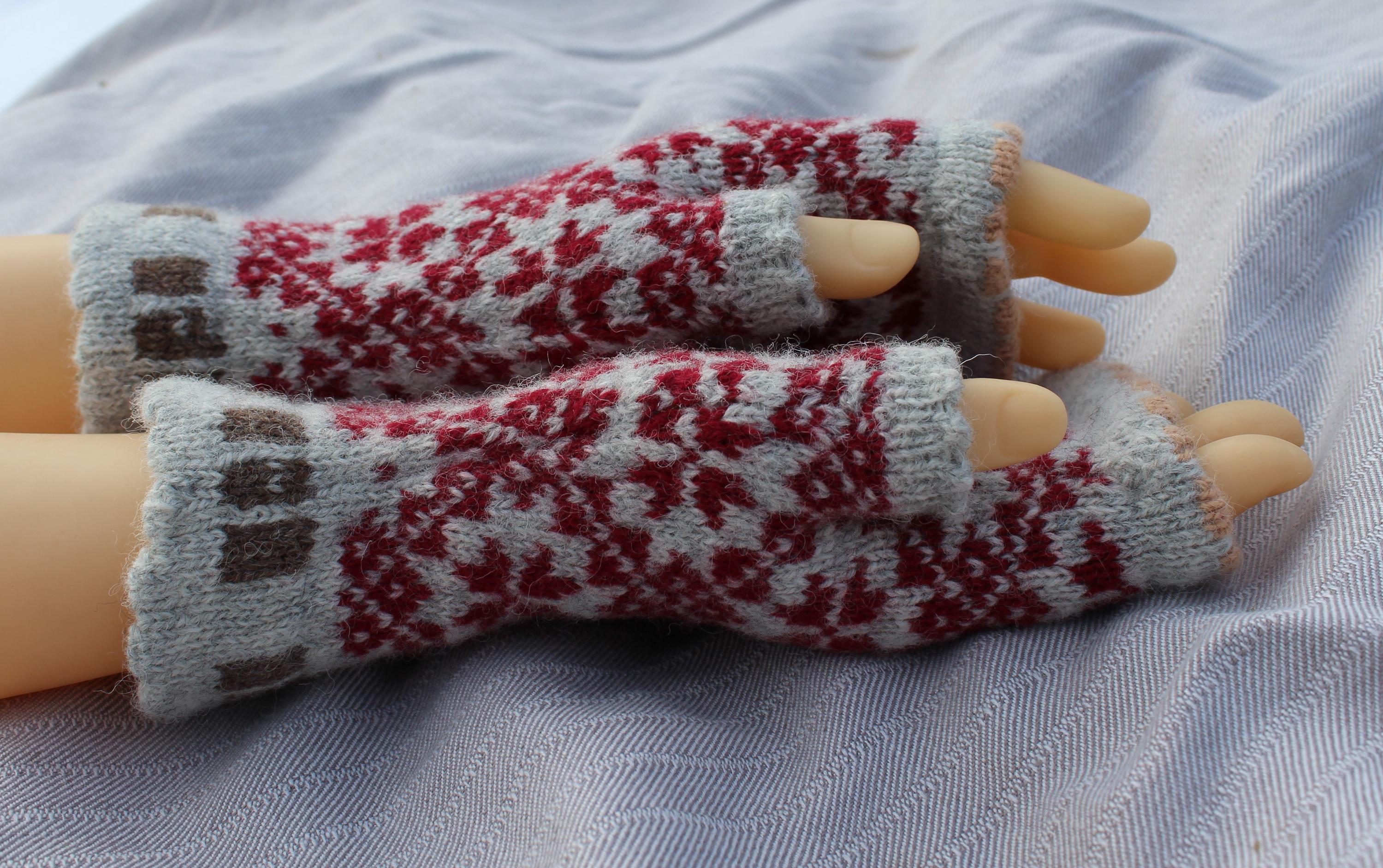 Pair of knitted fingerless gloves with a pattern on a fabric background
