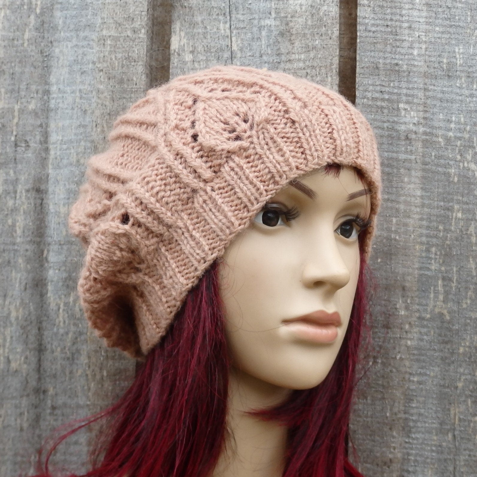 Knitted pink beanie on a mannequin head against a wooden background