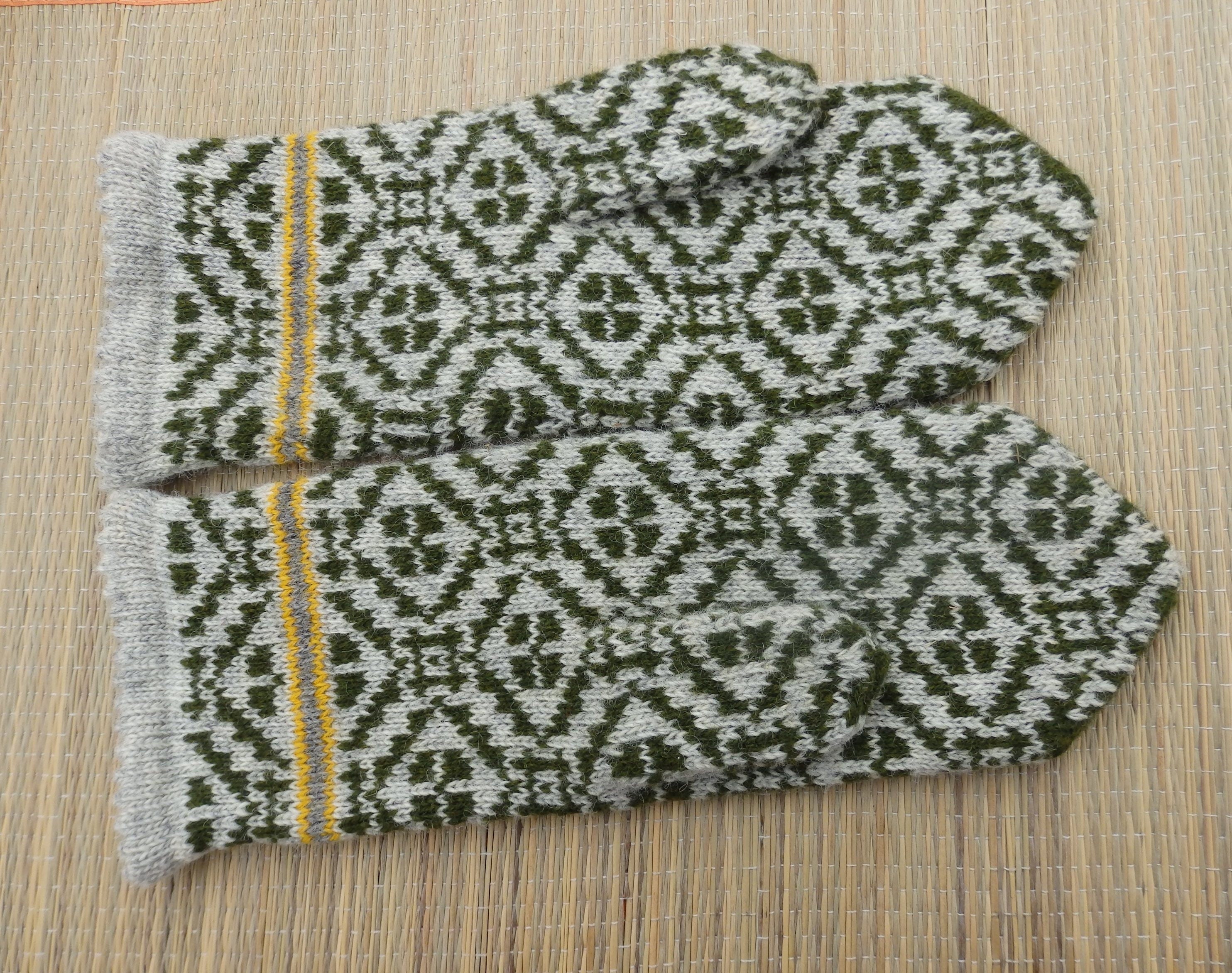 Pair of knitted mittens with a geometric pattern on a wooden surface